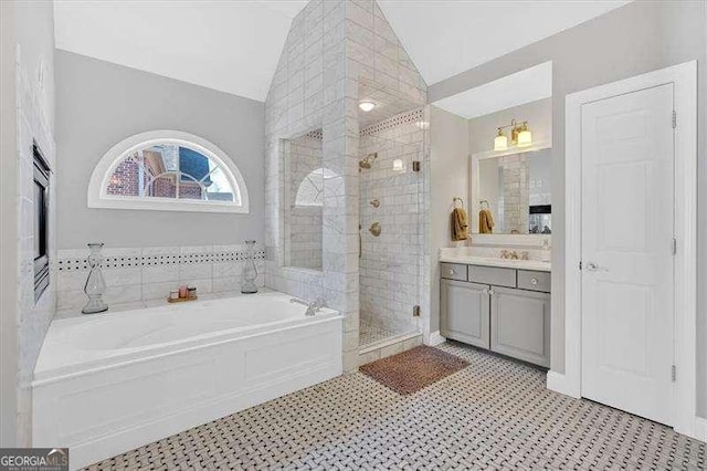 bathroom with vanity, a garden tub, a stall shower, and lofted ceiling