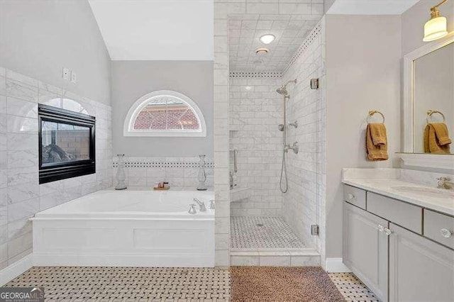 full bathroom with a garden tub, a shower stall, vanity, tile walls, and tile patterned floors
