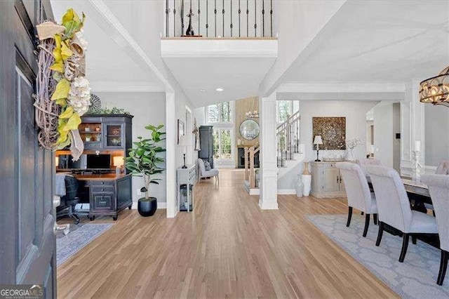 foyer entrance with wood finished floors, a towering ceiling, ornamental molding, and stairway