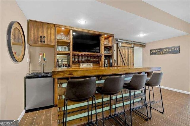 bar with baseboards, fridge, wood finish floors, and bar