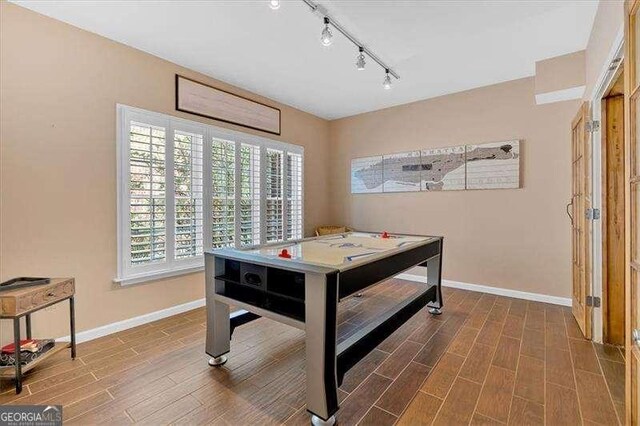 recreation room featuring rail lighting, baseboards, and wood tiled floor