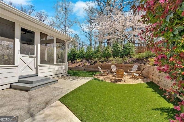 view of yard with a sunroom, an outdoor fire pit, and fence