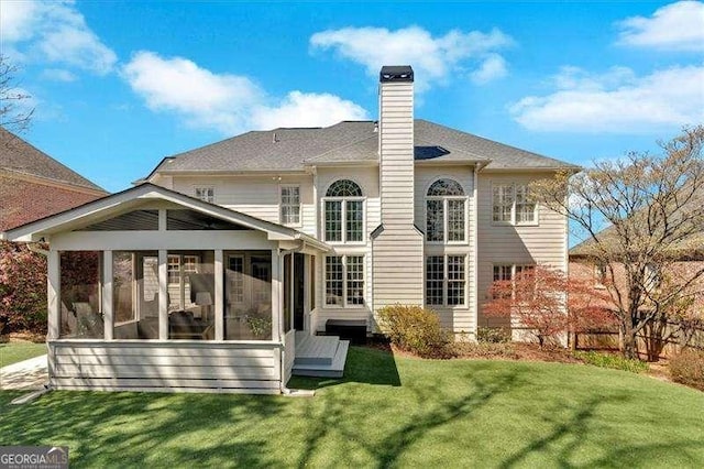 back of house with a chimney, a sunroom, and a lawn
