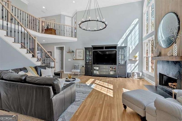 living area featuring baseboards, an inviting chandelier, stairs, a fireplace with flush hearth, and wood finished floors