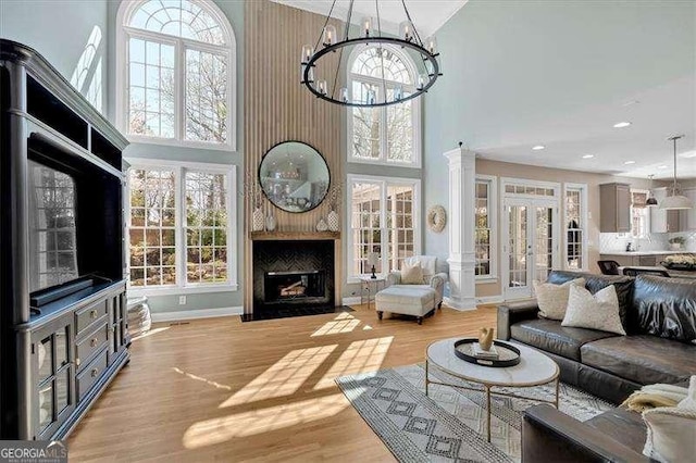 living room featuring a large fireplace, a chandelier, recessed lighting, french doors, and light wood-style floors