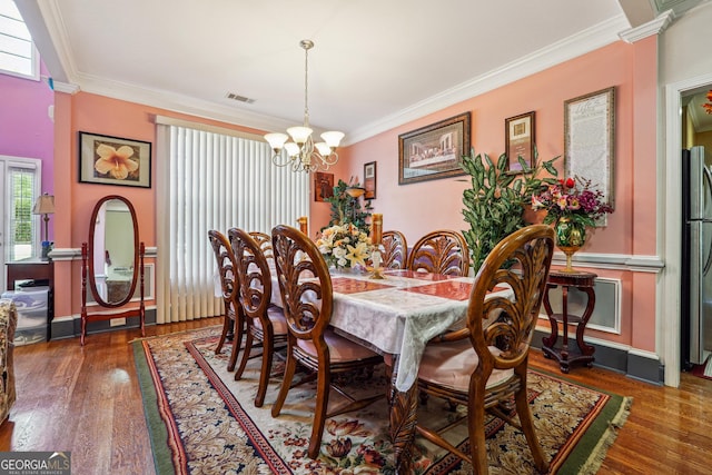 dining space with ornamental molding, a notable chandelier, wood finished floors, and visible vents