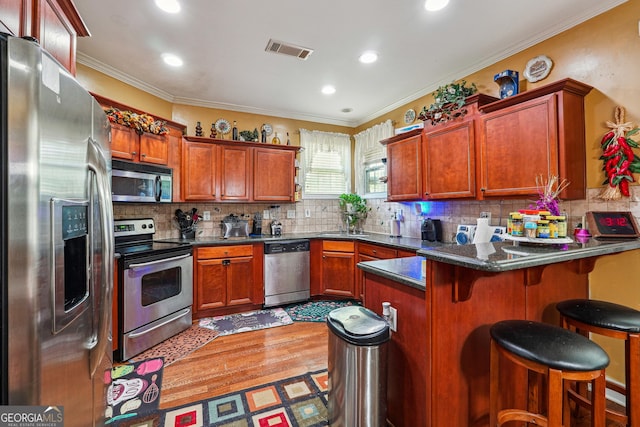 kitchen featuring backsplash, a peninsula, appliances with stainless steel finishes, and visible vents