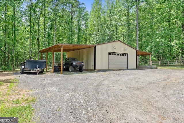exterior space with driveway, fence, a view of trees, and a detached garage