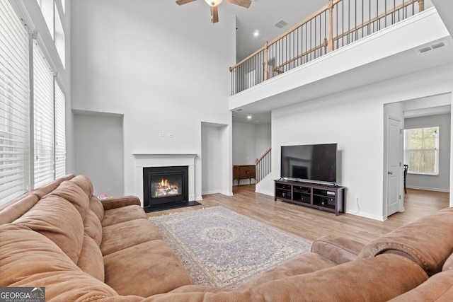 133 Bastian Rd, Mcdonough, GA 30252 - living room featuring a high ceiling, ceiling fan, wood finished floors, a fireplace with flush hearth, and stairway
