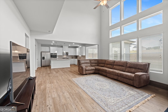 133 Bastian Rd, Mcdonough, GA 30252 - living room featuring a ceiling fan, a towering ceiling, and light wood-style floors
