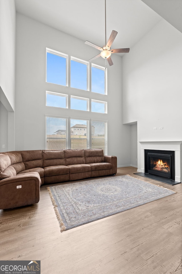 133 Bastian Rd, Mcdonough, GA 30252 - living room featuring a high ceiling, a ceiling fan, a fireplace with flush hearth, and wood finished floors