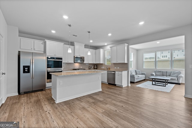 133 Bastian Rd, Mcdonough, GA 30252 - kitchen featuring appliances with stainless steel finishes, open floor plan, white cabinets, decorative backsplash, and a kitchen island