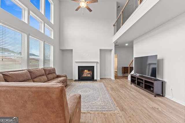 133 Bastian Rd, Mcdonough, GA 30252 - living room featuring a ceiling fan, wood finished floors, a high ceiling, a glass covered fireplace, and stairs