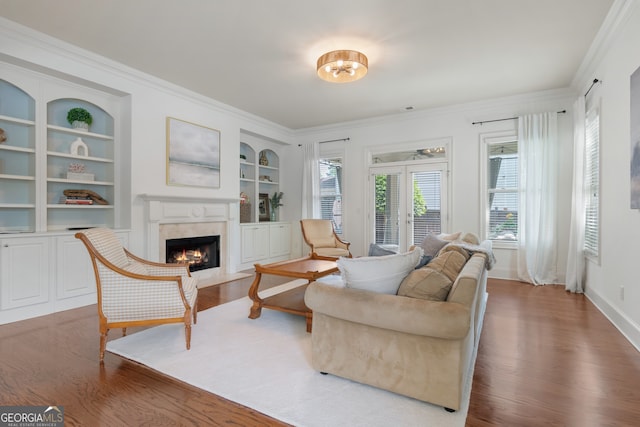 living area with a high end fireplace, crown molding, and wood finished floors