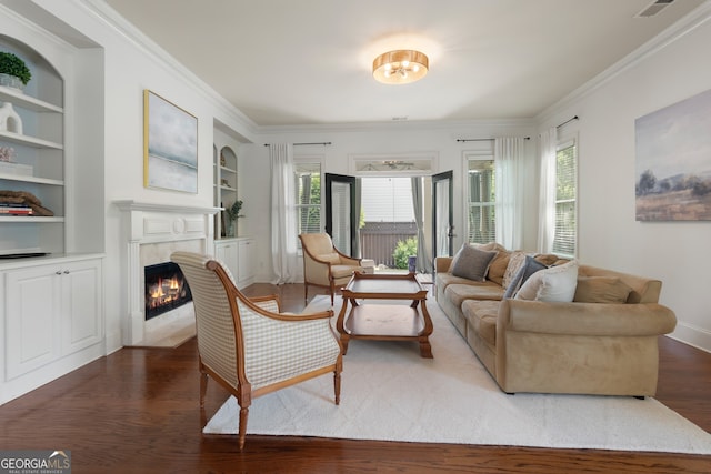 sitting room with crown molding, visible vents, built in features, dark wood finished floors, and a premium fireplace
