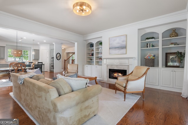 living area featuring built in features, ornamental molding, wood finished floors, and a premium fireplace
