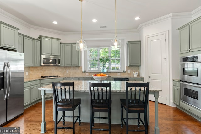 kitchen featuring a center island, stainless steel appliances, decorative light fixtures, tasteful backsplash, and visible vents