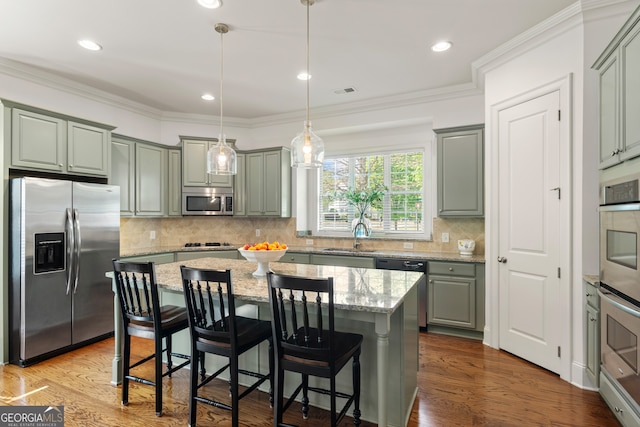 kitchen featuring a center island, gray cabinets, light stone counters, a sink, and stainless steel appliances
