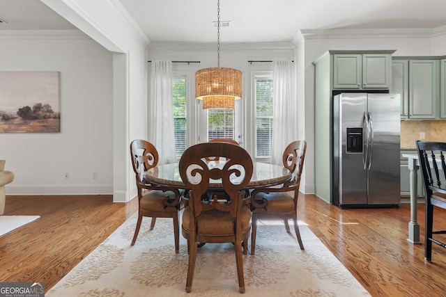 dining area featuring baseboards, ornamental molding, wood finished floors, and visible vents