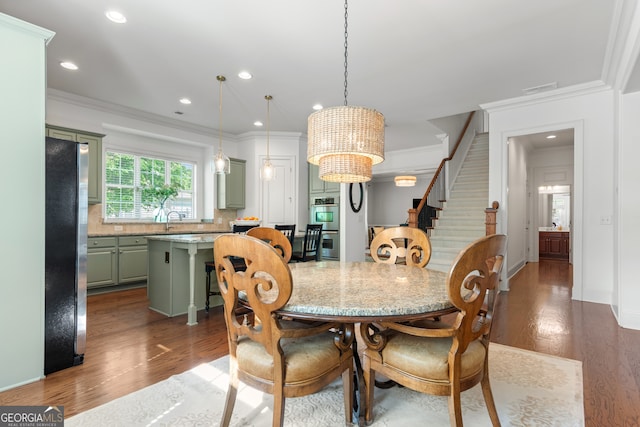 dining area with stairway, ornamental molding, wood finished floors, and a notable chandelier