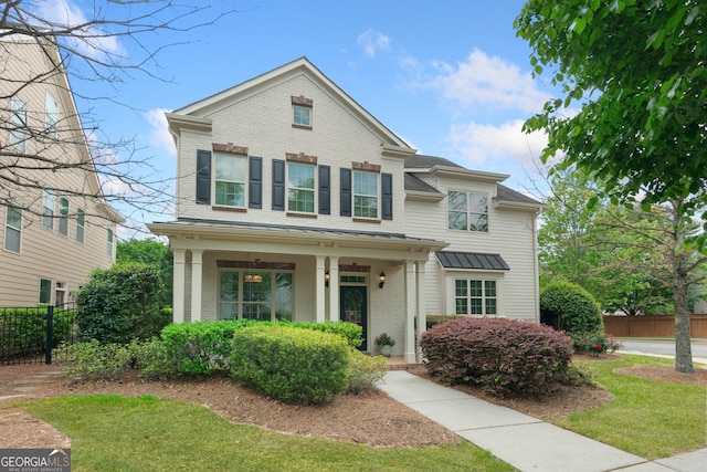 view of front of property with a porch, brick siding, and fence