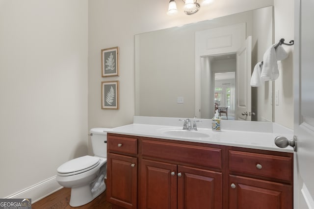 bathroom featuring vanity, baseboards, toilet, and wood finished floors