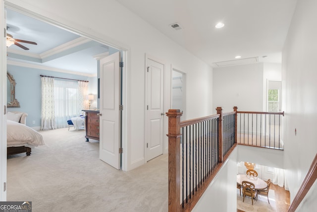 hallway with attic access, visible vents, crown molding, an upstairs landing, and light carpet