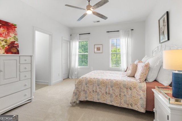 bedroom with baseboards, light carpet, a ceiling fan, and visible vents