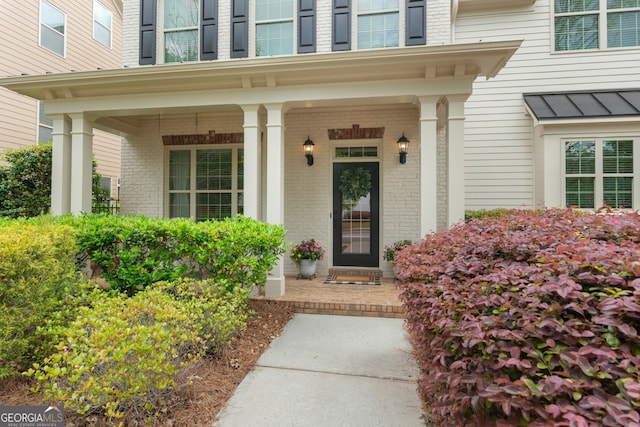 property entrance with a porch, brick siding, a standing seam roof, and metal roof