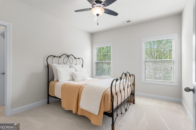 bedroom featuring visible vents, a ceiling fan, baseboards, and light colored carpet
