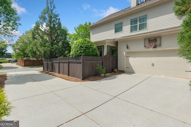 view of home's exterior featuring fence, an attached garage, and concrete driveway