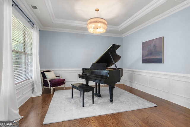 living area featuring crown molding, wainscoting, wood finished floors, a raised ceiling, and a chandelier