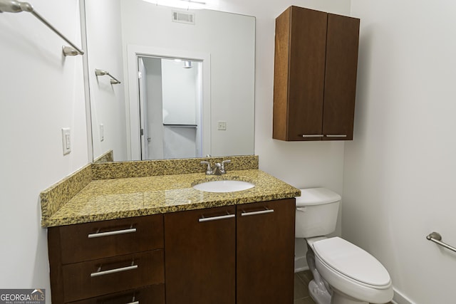 half bathroom with baseboards, visible vents, toilet, and vanity