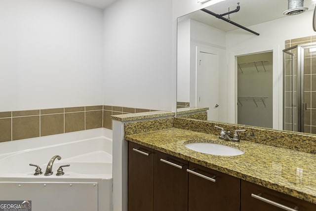 full bath featuring vanity, a walk in closet, a stall shower, visible vents, and a bath