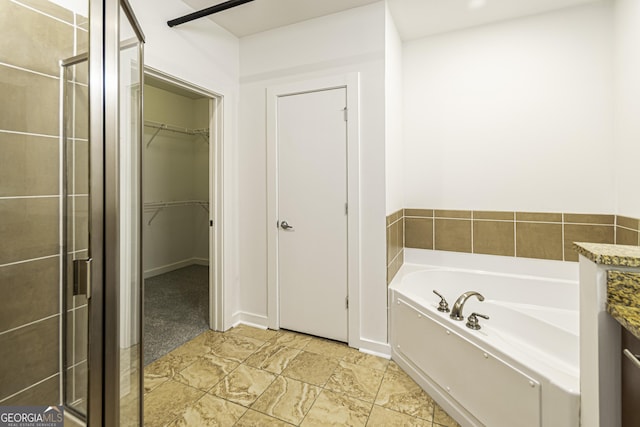 bathroom featuring a spacious closet, a stall shower, and a garden tub