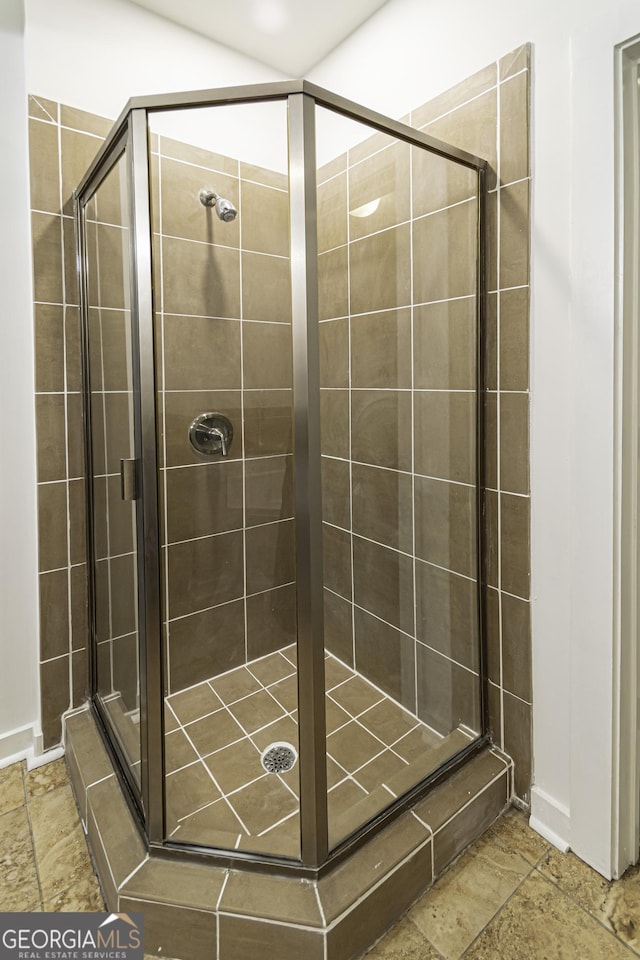 full bathroom with stone tile floors and a shower stall