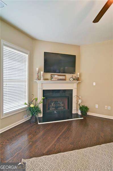 4854 Allston Ln, Peachtree Corners, GA 30092 - living area with baseboards, wood finished floors, a fireplace with raised hearth, and a ceiling fan