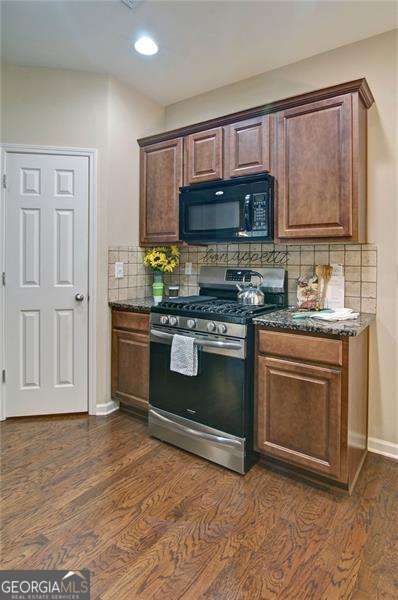 4854 Allston Ln, Peachtree Corners, GA 30092 - kitchen with dark wood-style floors, black microwave, backsplash, and stainless steel gas range
