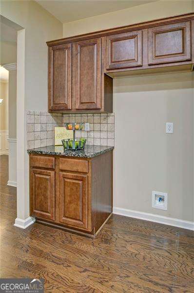 4854 Allston Ln, Peachtree Corners, GA 30092 - kitchen with baseboards, backsplash, dark stone countertops, and dark wood-type flooring