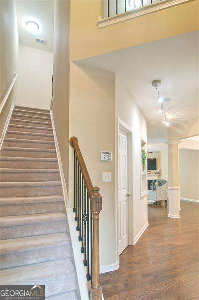 4854 Allston Ln, Peachtree Corners, GA 30092 - staircase featuring ornate columns, baseboards, visible vents, and wood finished floors