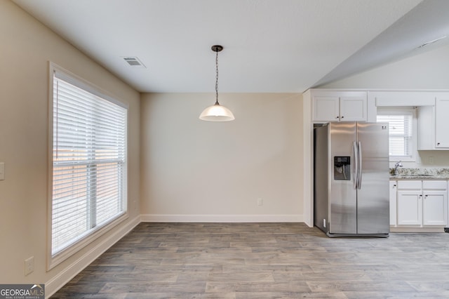 174 Livingston Ct, Winder, GA 30680 - kitchen featuring stainless steel refrigerator with ice dispenser, white cabinetry, light wood-style flooring, and hanging light fixtures