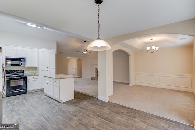 174 Livingston Ct, Winder, GA 30680 - kitchen with black appliances, open floor plan, arched walkways, light wood finished floors, and a center island