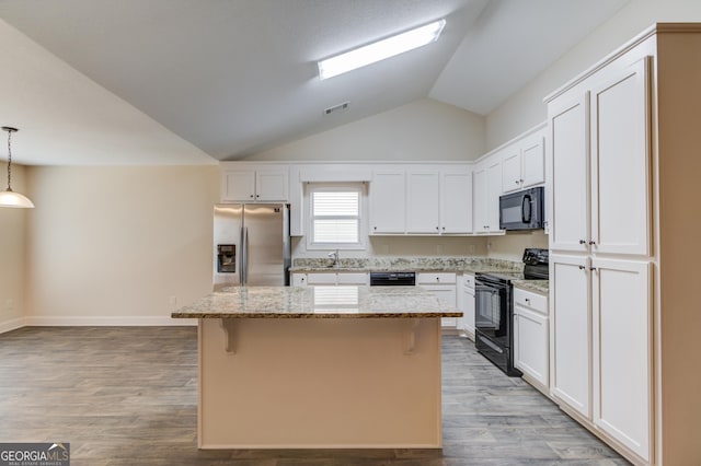 174 Livingston Ct, Winder, GA 30680 - kitchen featuring black appliances, a kitchen island, white cabinetry, light stone countertops, and vaulted ceiling