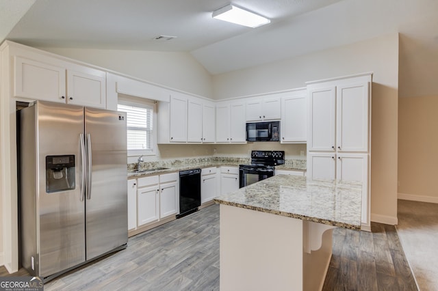 174 Livingston Ct, Winder, GA 30680 - kitchen featuring black appliances, lofted ceiling, light stone countertops, light wood-style floors, and white cabinets