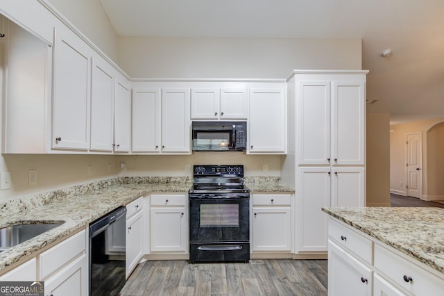 174 Livingston Ct, Winder, GA 30680 - kitchen with black appliances, white cabinetry, light wood-style flooring, and light stone countertops