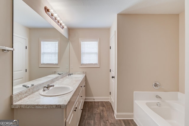 174 Livingston Ct, Winder, GA 30680 - full bathroom featuring double vanity, a garden tub, and wood finished floors