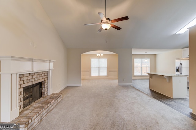 174 Livingston Ct, Winder, GA 30680 - unfurnished living room with a ceiling fan, light carpet, arched walkways, lofted ceiling, and a brick fireplace
