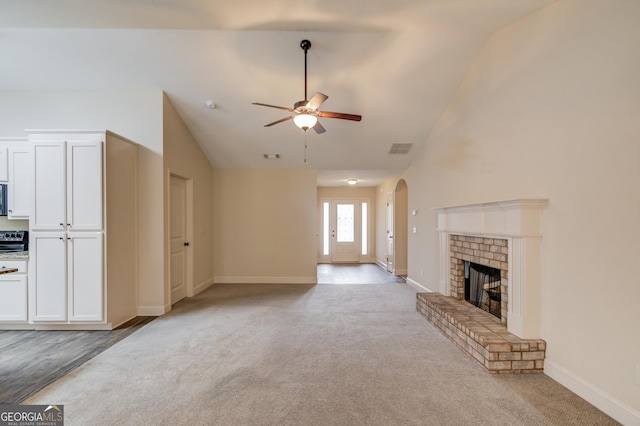 174 Livingston Ct, Winder, GA 30680 - unfurnished living room with carpet floors, ceiling fan, arched walkways, a fireplace, and high vaulted ceiling