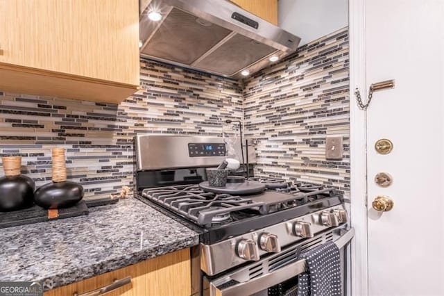 6851 Roswell Rd Unit A-12, Atlanta, GA 30328 - kitchen featuring stainless steel gas range oven, wall chimney range hood, decorative backsplash, and dark stone counters