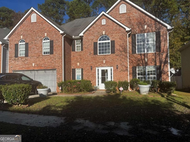 colonial house featuring an attached garage, brick siding, and a front yard